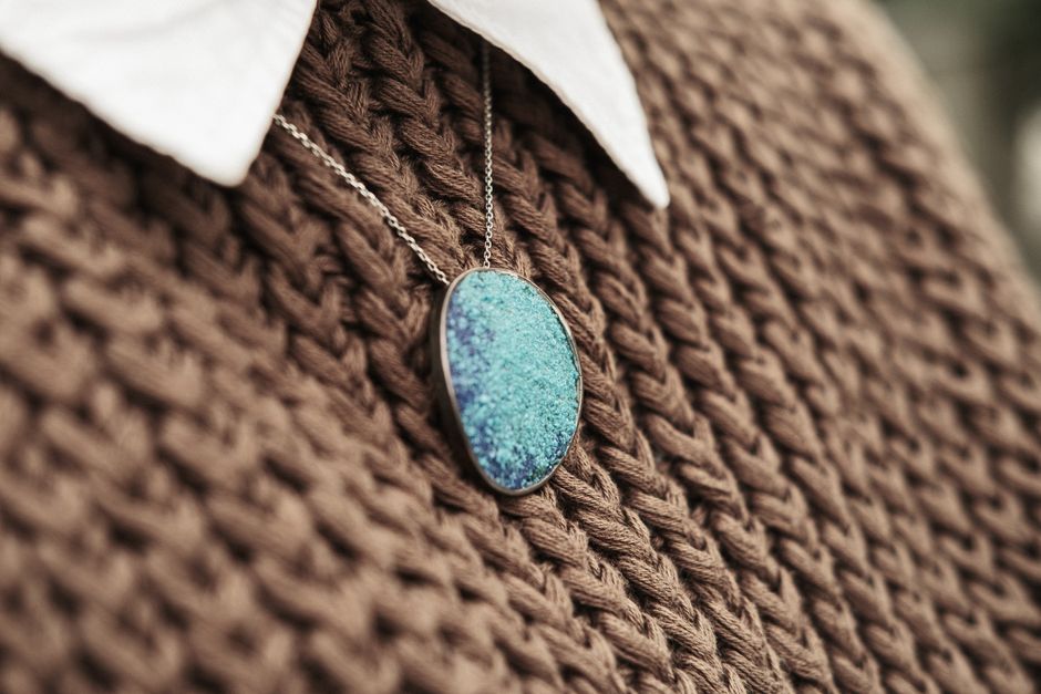 Stylish blue pendant necklace resting on a brown knit sweater