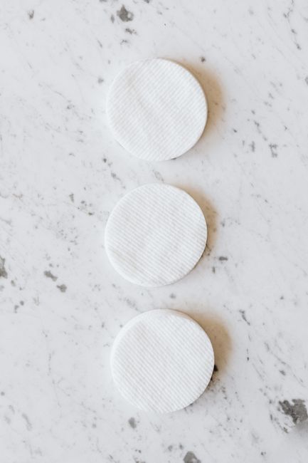 Row of clean round white cotton pads on a marble surface