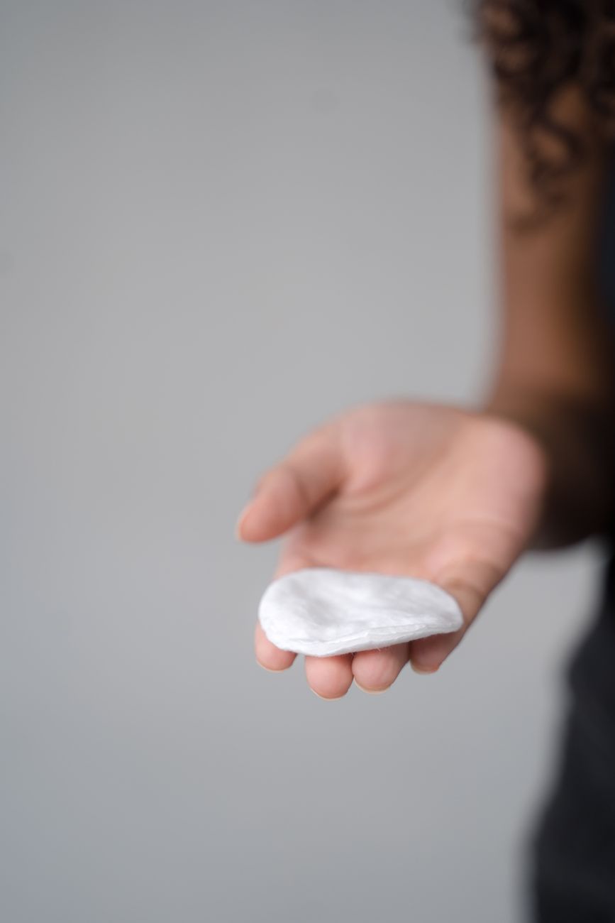 Hand holding a cotton pad used for cleaning a piercing