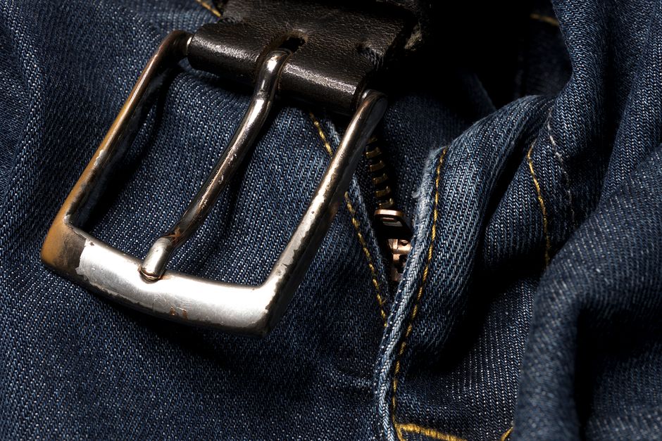 Detailed view of denim jeans with a metal buckle and zipper
