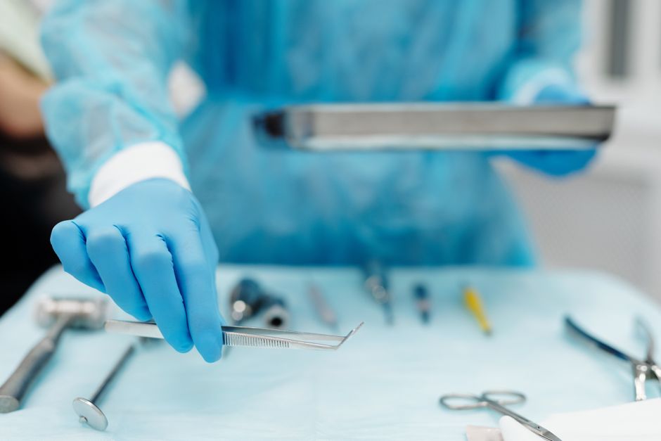 Blue-gloved hand handling surgical tools in a medical setting