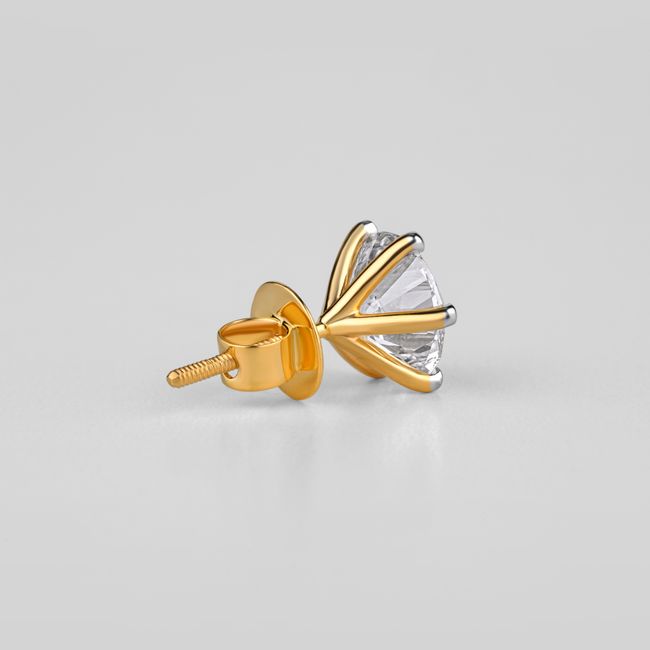 Close-up of a gold and diamond solitaire earring on a neutral background
