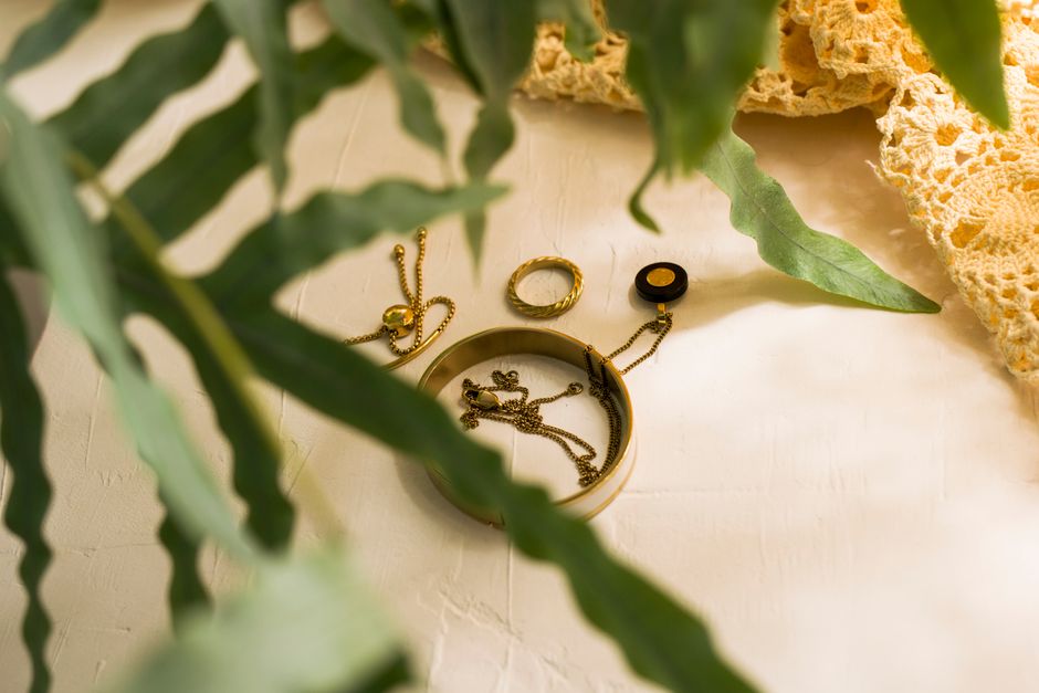 Gold jewelry pieces including bracelets and rings on a textured surface