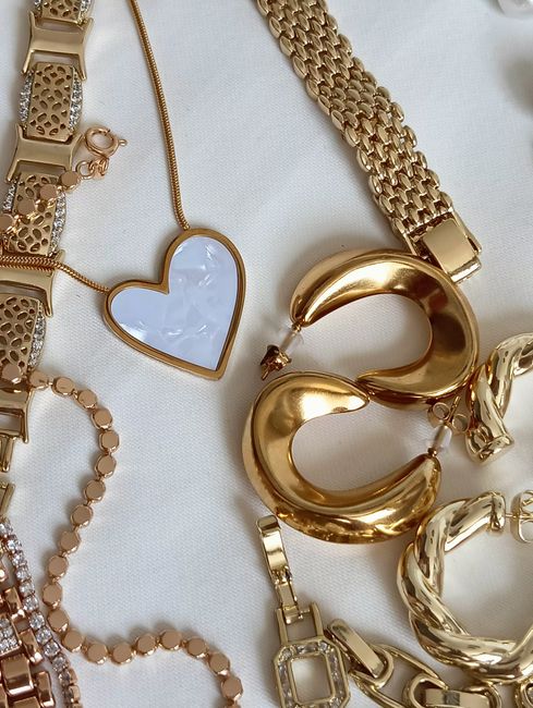 Stylish flat lay of gold jewelry featuring a heart necklace, bracelets, and chains