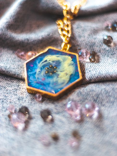 Luxurious gold necklace featuring a hexagonal blue resin pendant with decorative gems