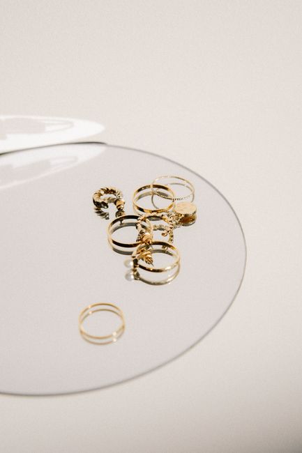 Stylish collection of gold rings displayed on a reflective surface