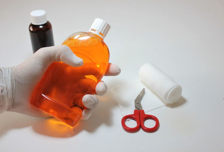 Hand holding an antiseptic bottle with first aid items