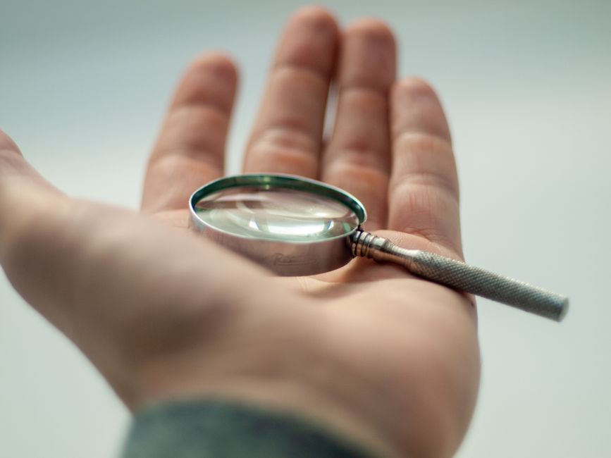 Detailed close-up of a hand holding a magnifying glass