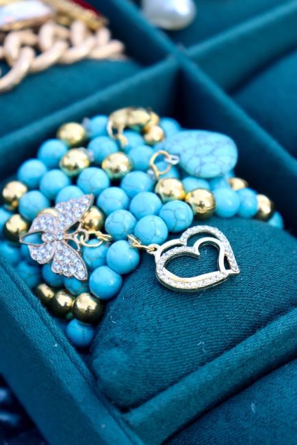 Close-up of turquoise and gold jewelry with a heart charm in a velvet box