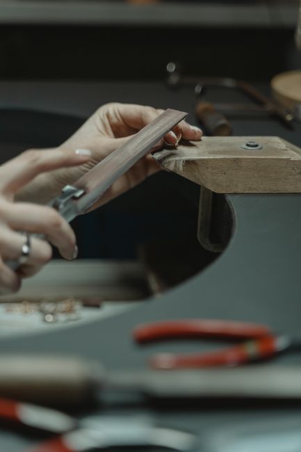 Jeweler using a file on metal in an artisan workshop