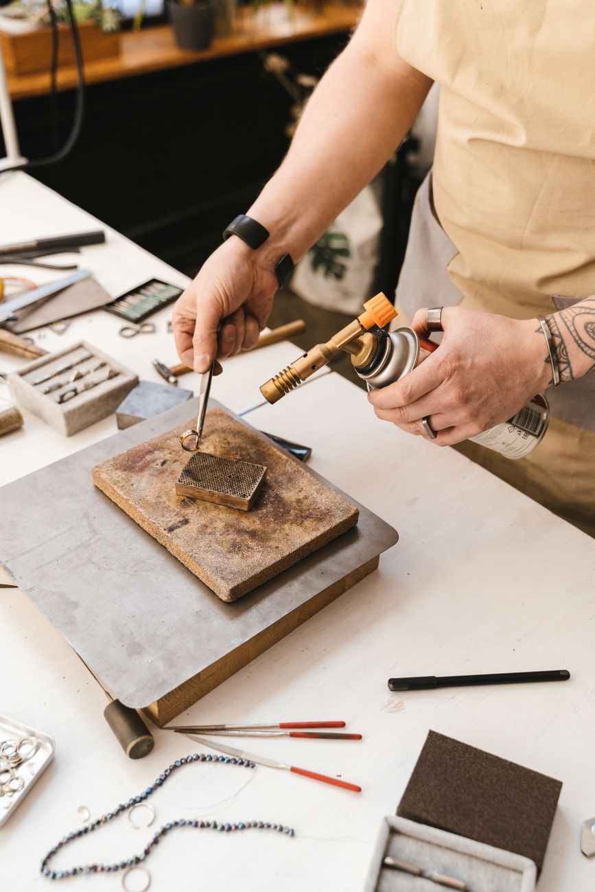 Jeweler using a torch to work metal in a workshop