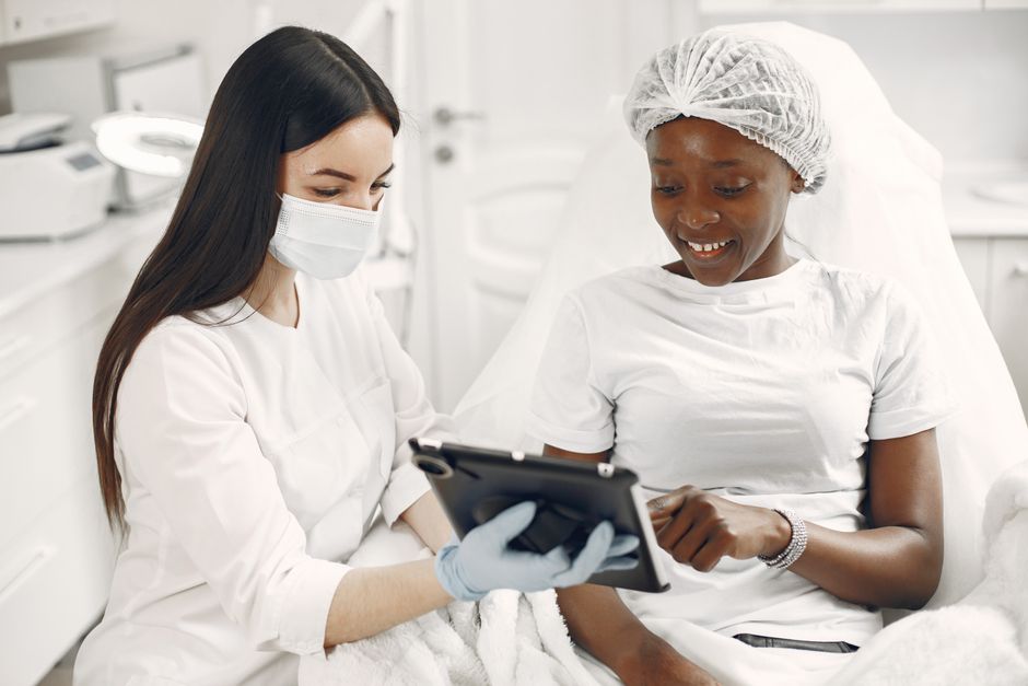 Smiling patient and dermatologist using tablet during consultation