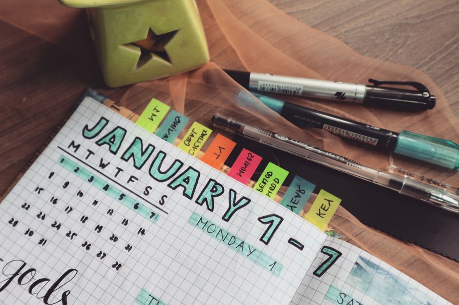 A detailed planner with goals and colorful tabs on a wooden desk