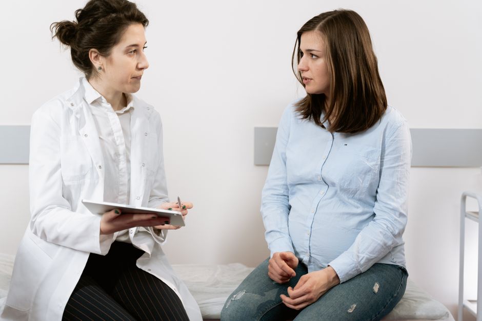 A pregnant woman consulting with a female doctor in a medical clinic setting