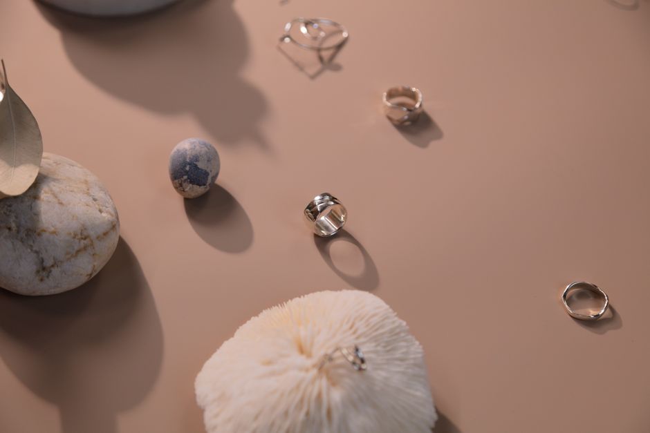 Minimalist arrangement of silver rings with stones and a feather