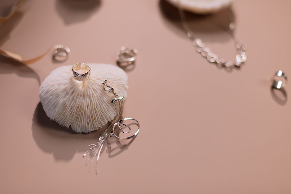 Stylish silver rings and necklace displayed on a soft pink background
