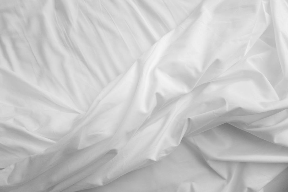 Elegant close-up view of white satin bed sheets with soft texture
