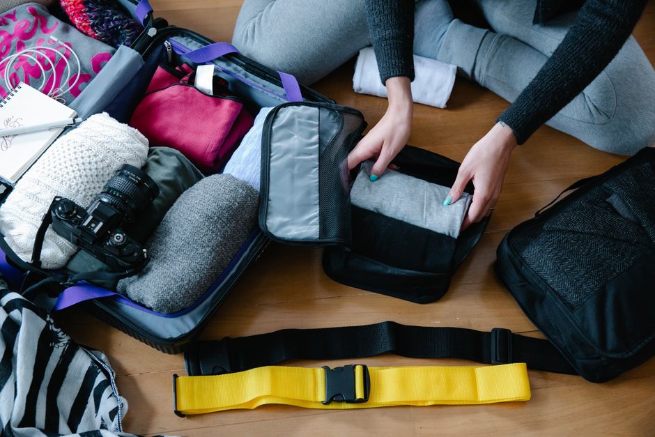 A woman arranging clothes and accessories into a suitcase